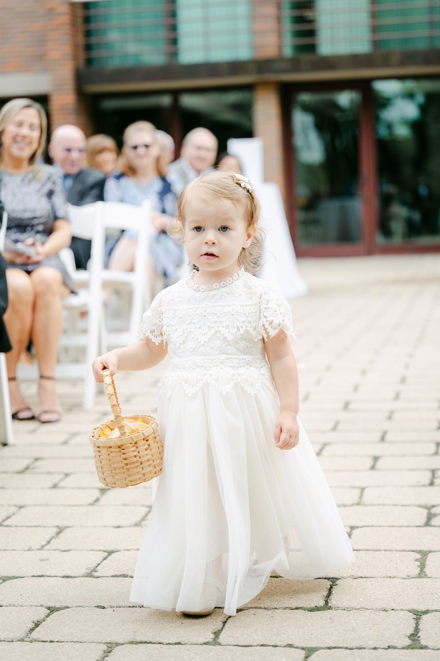 Three sequential photos show a flower girl in a white dress carrying a basket along a stone walkway. - Hyatt Lodge Oak Brook