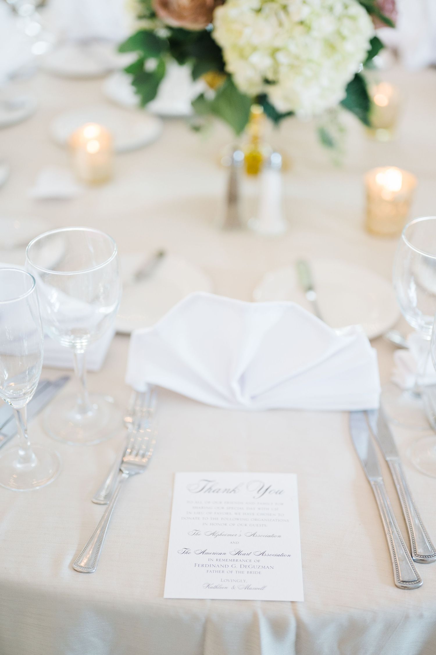Elegant wedding table setting with menu card, folded napkin, and floral centerpiece.