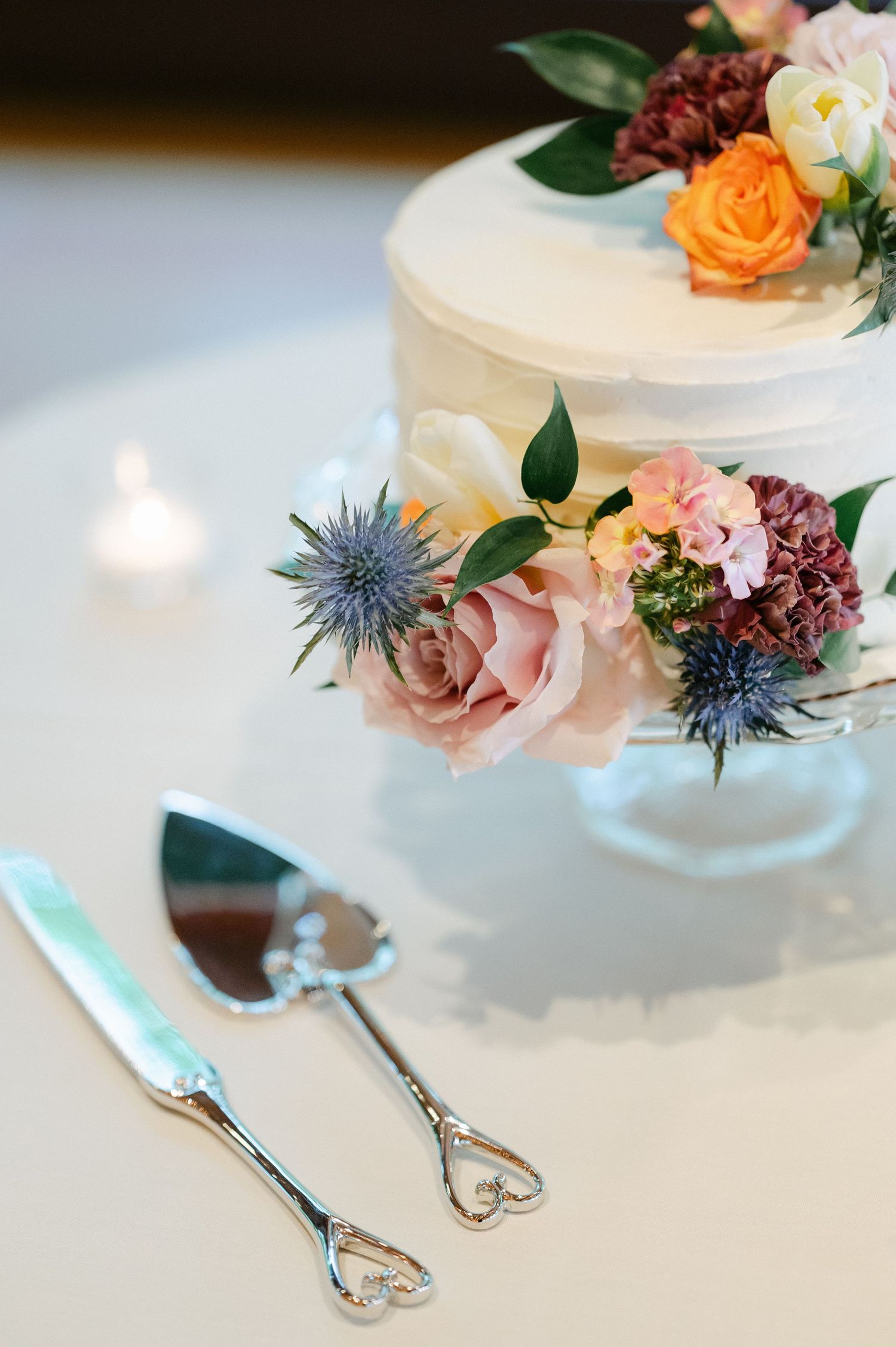 Wedding cake decorated with fresh flowers and ornate silver serving utensils. - Hyatt Lodge Oak Brook Wedding
