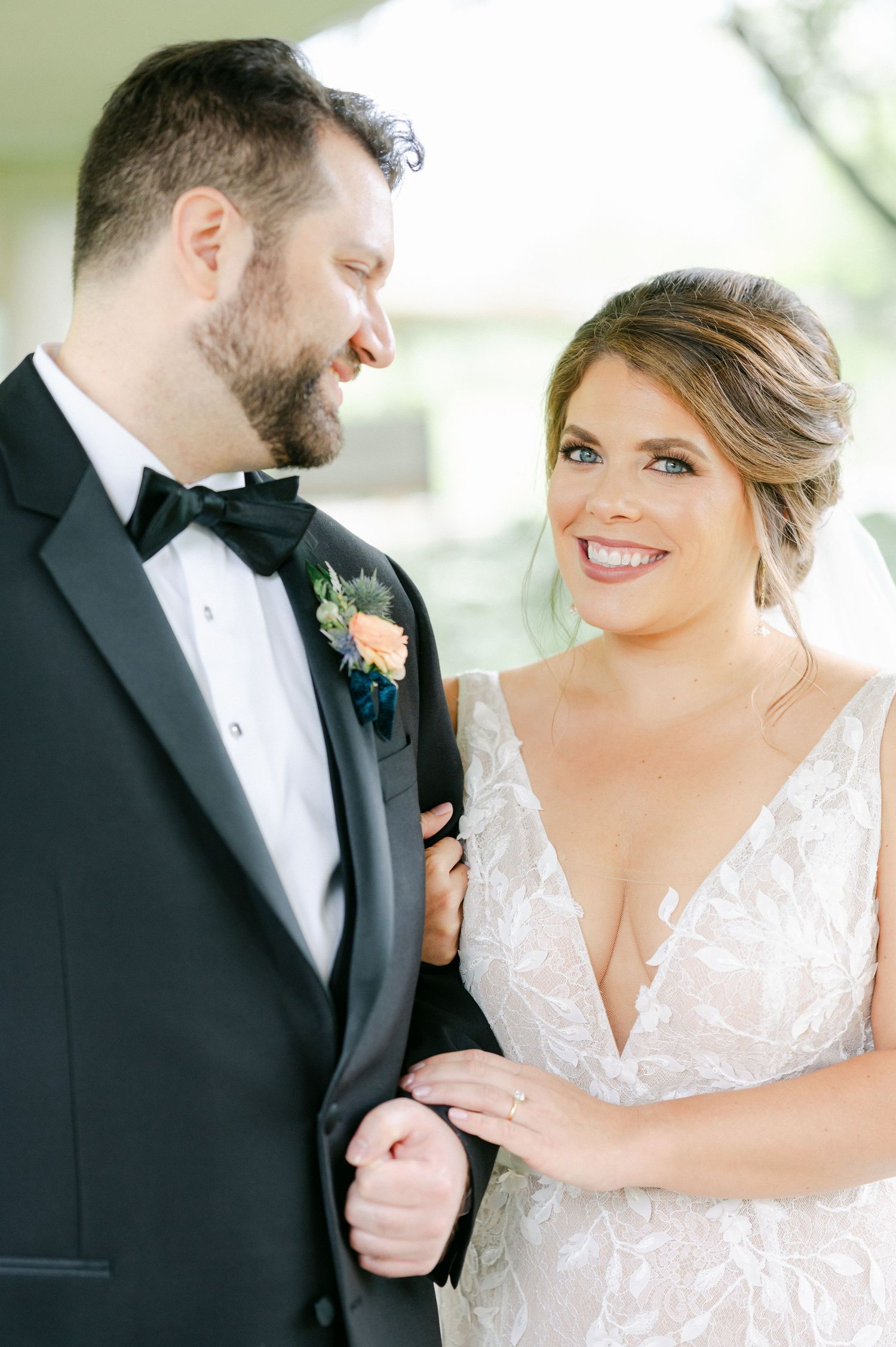A romantic moment between newlyweds in formal wedding attire sharing laughter and tender gestures outdoors. - Hyatt Lodge Oak Brook