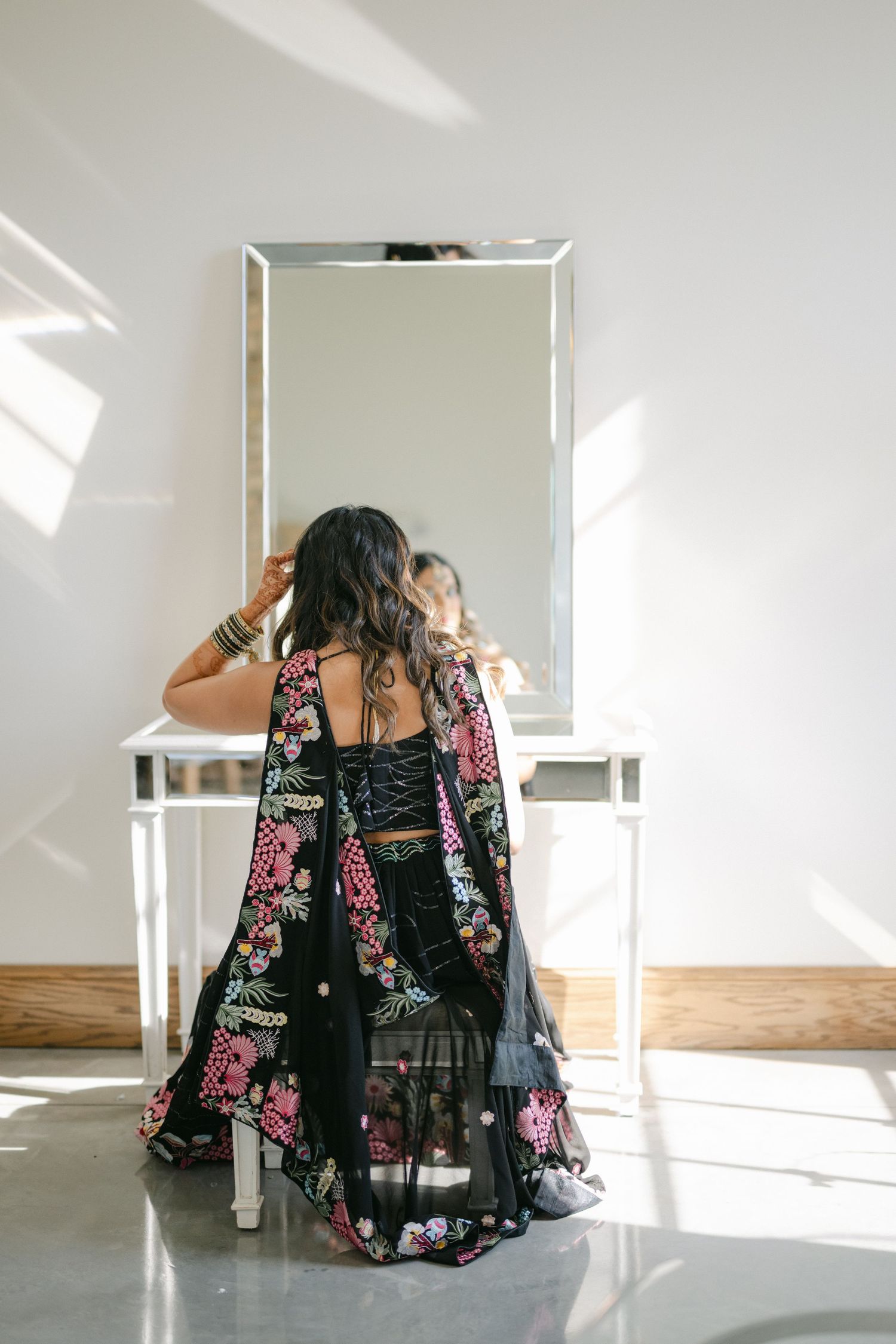 A person in a black and pink floral dress sits on a white floor in a bright, minimalist studio space. - The Brix on the Fox