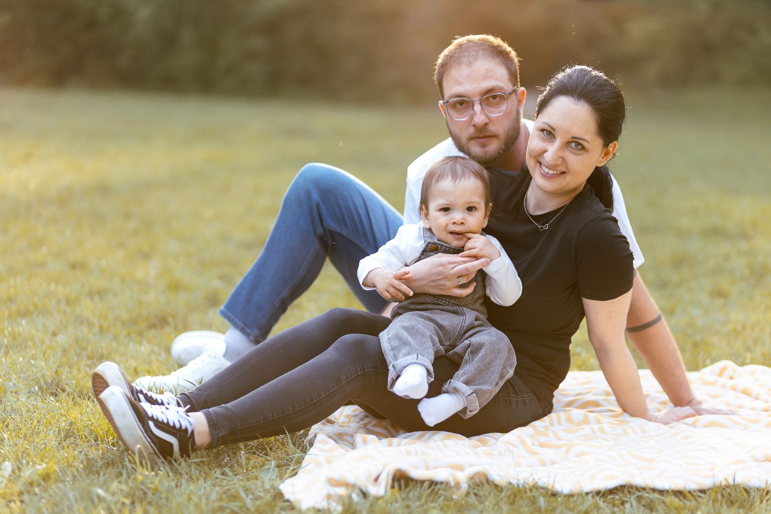 A family lounging on grass during a sunset photoshoot in a park.