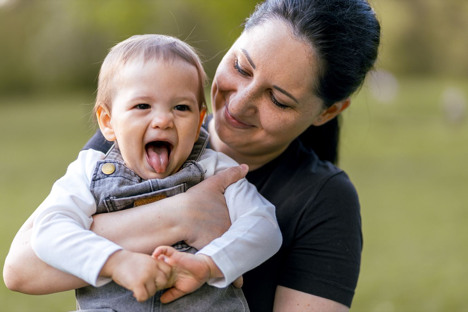 Playful baby making silly faces during outdoor family photoshoot.