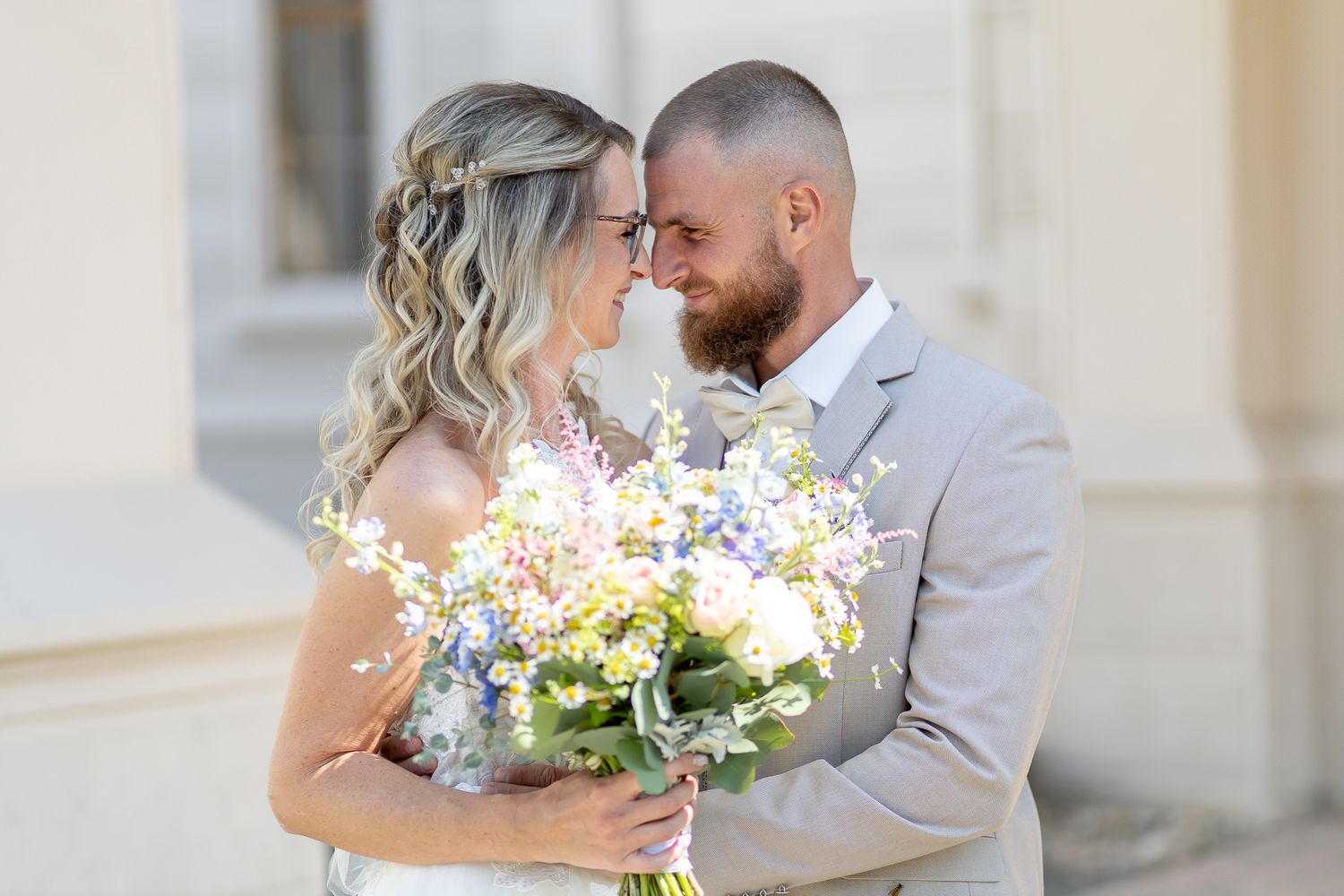 A couple shares an intimate moment during their outdoor wedding ceremony with floral arrangements.