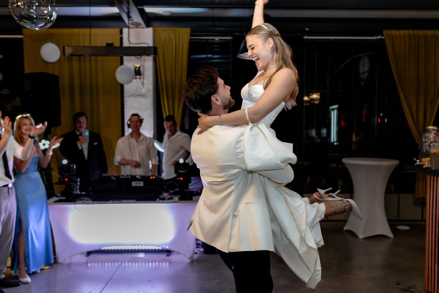 Newlyweds share a romantic dance with dramatic lighting effects on the dance floor.