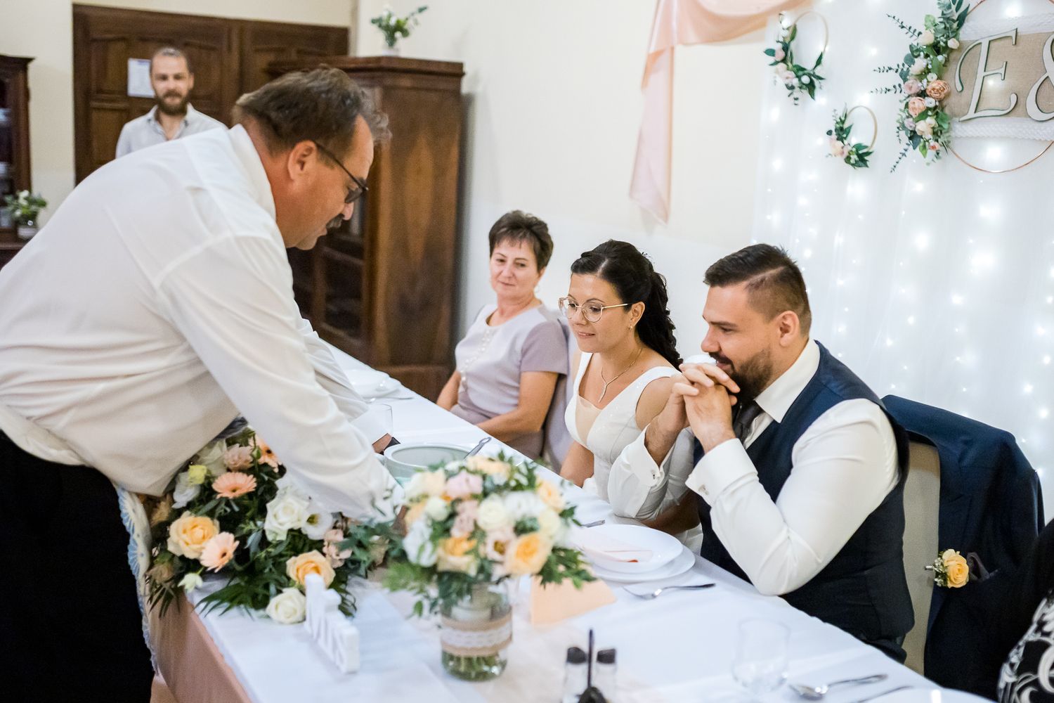 Wedding guests enjoying a celebratory dinner reception at a rustic venue with wooden beams and elegant decor.