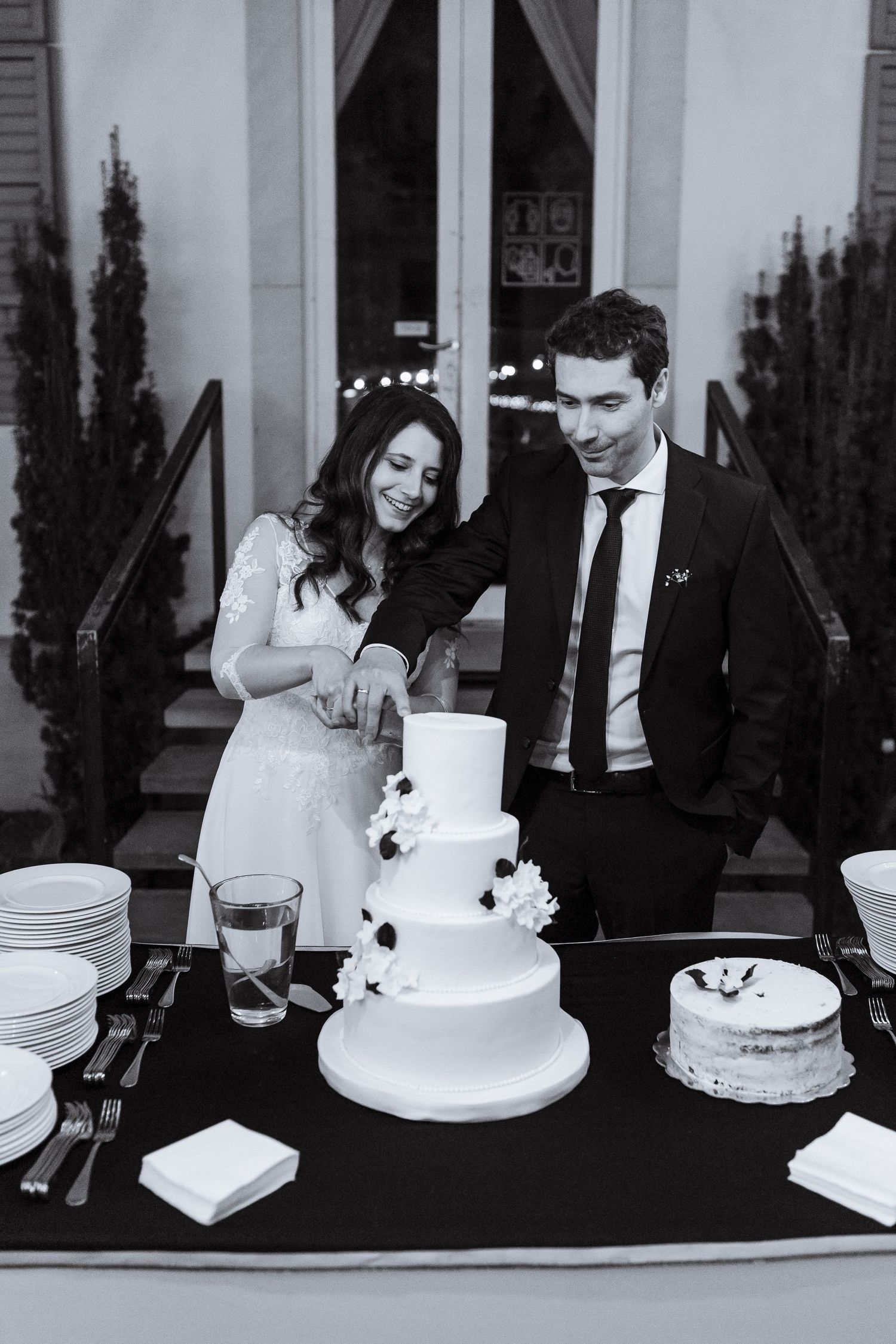 Black and white photo sequence showing a couple cutting their white tiered wedding cake at a reception.
