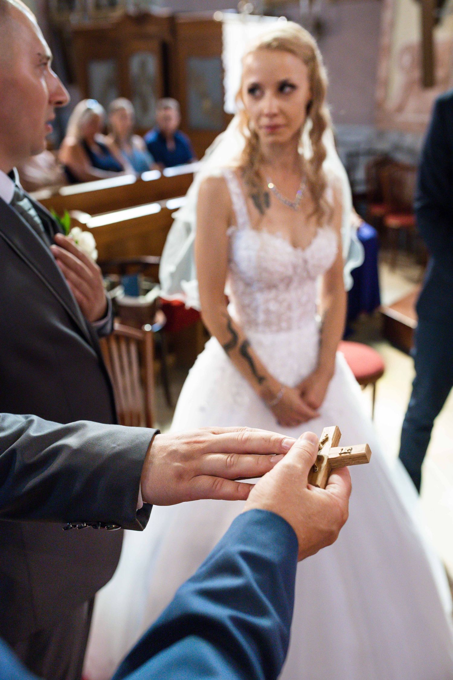 Wedding ceremony moment showing hands exchanging rings in a church setting.