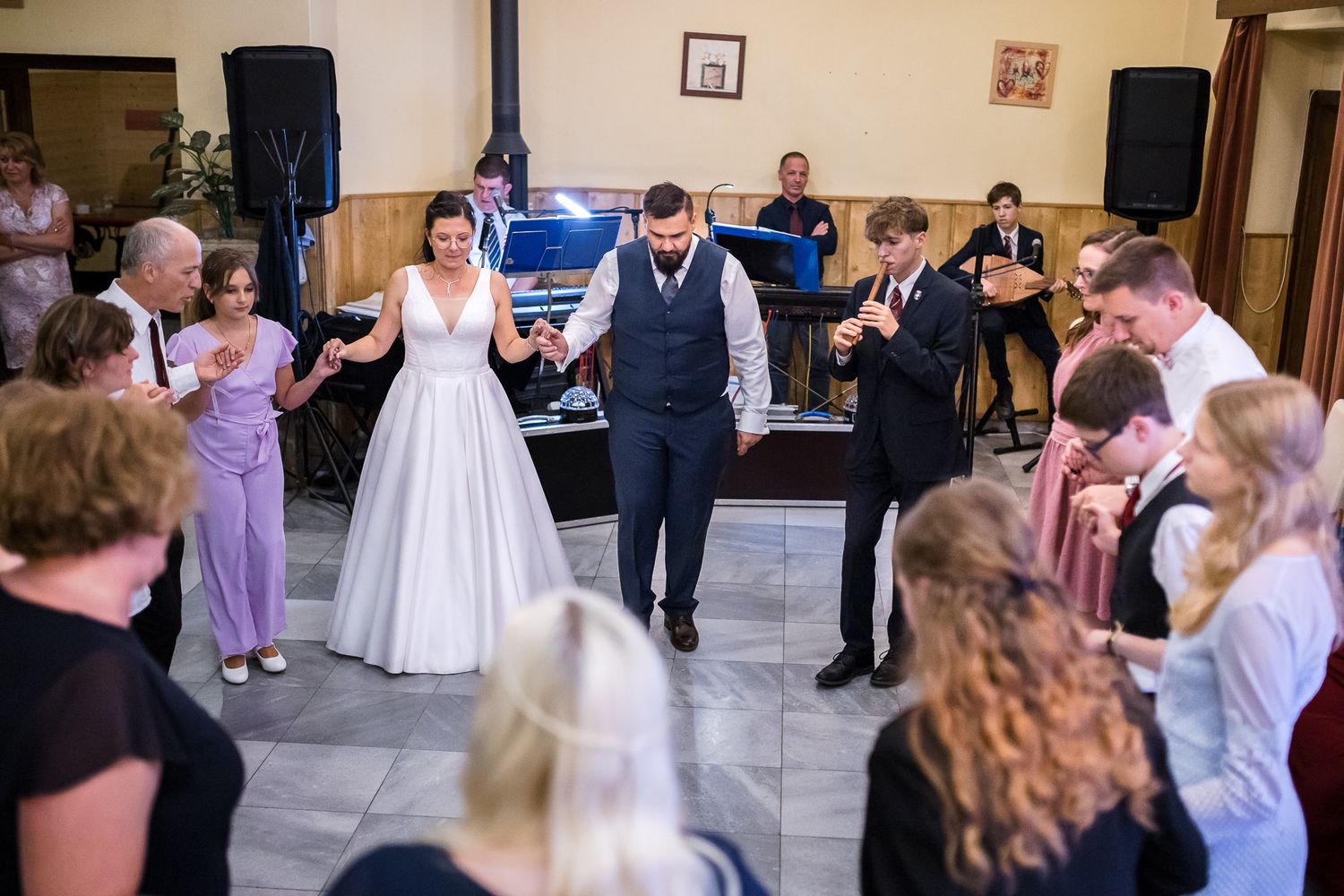 Wedding guests dance together in a line formation during a reception celebration on a dance floor.