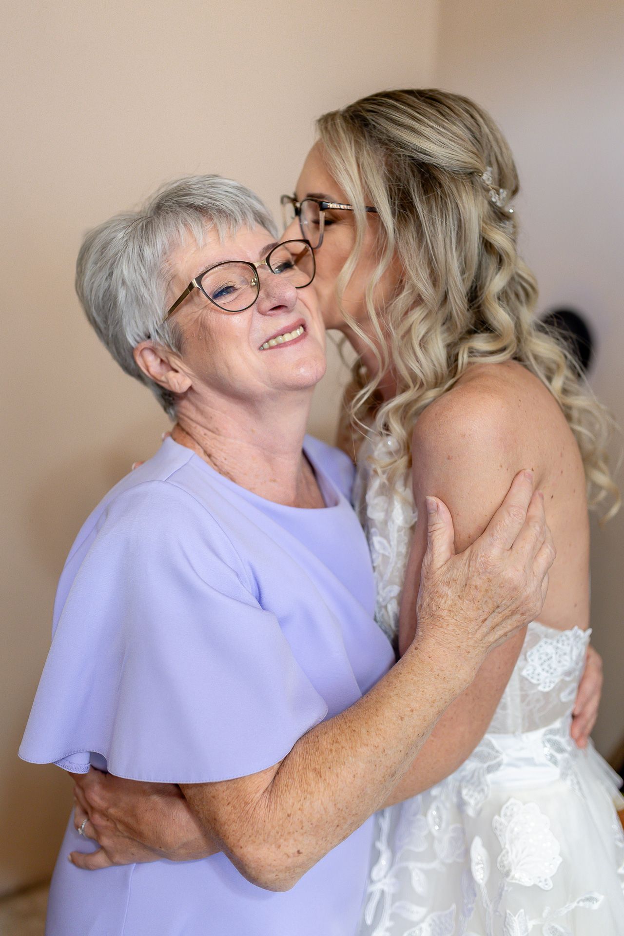 A tender moment shared between two people embracing, one wearing a lavender top and one in a white wedding dress.