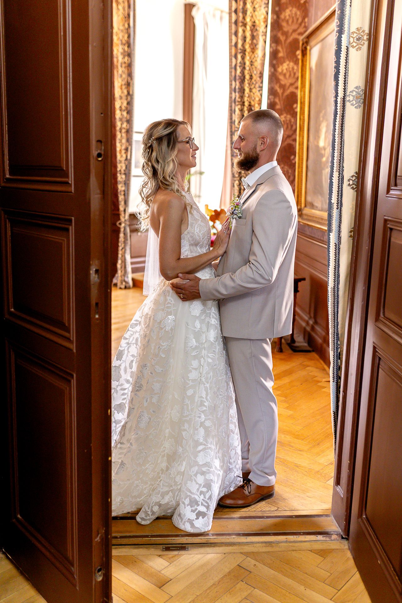 A romantic first look sequence between a bride and groom in an elegant palace hallway with wooden doors.