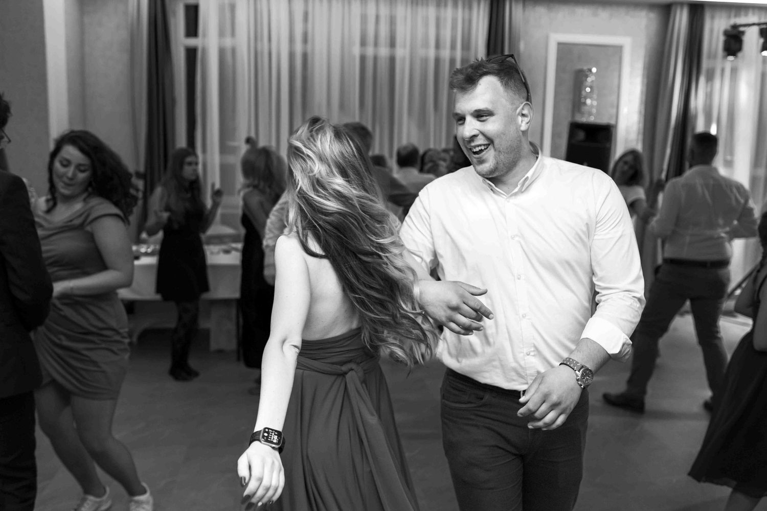 Dancers in a ballroom dance class practice their steps together in a bright studio space.