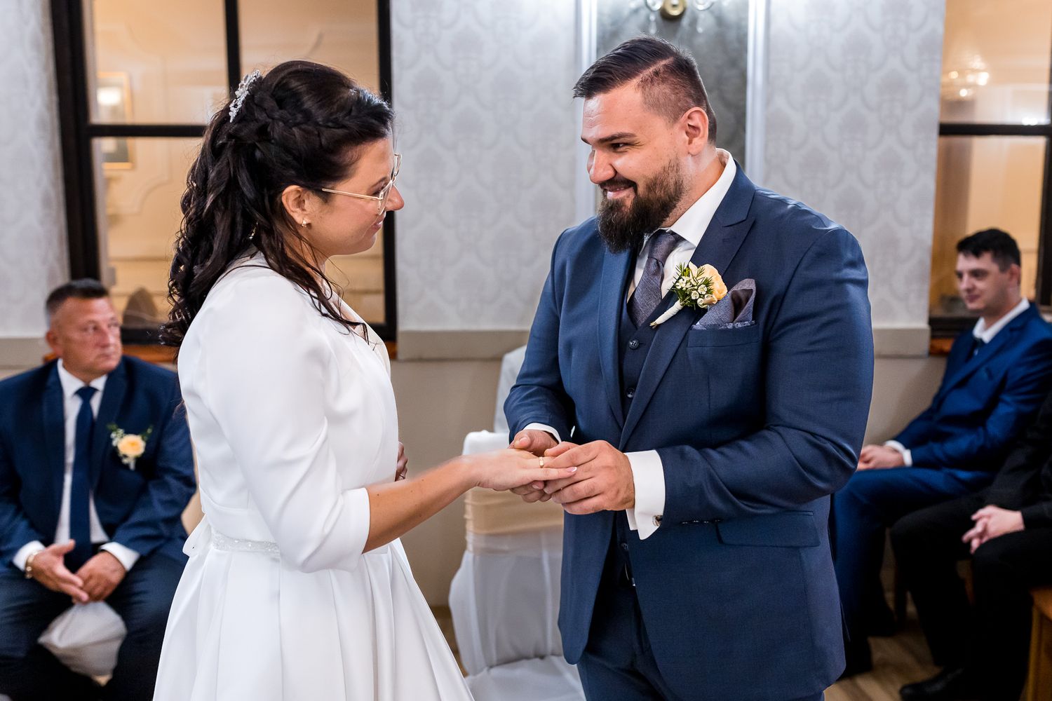 A bride and groom share a joyful moment together during their wedding ceremony at an elegant indoor venue.