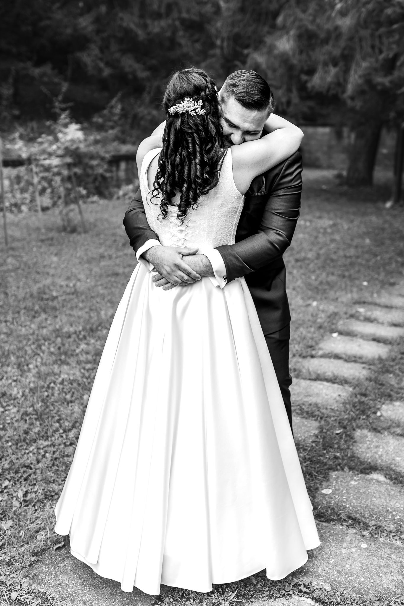 A romantic black and white wedding photo series showing a couple embracing in an outdoor garden setting.