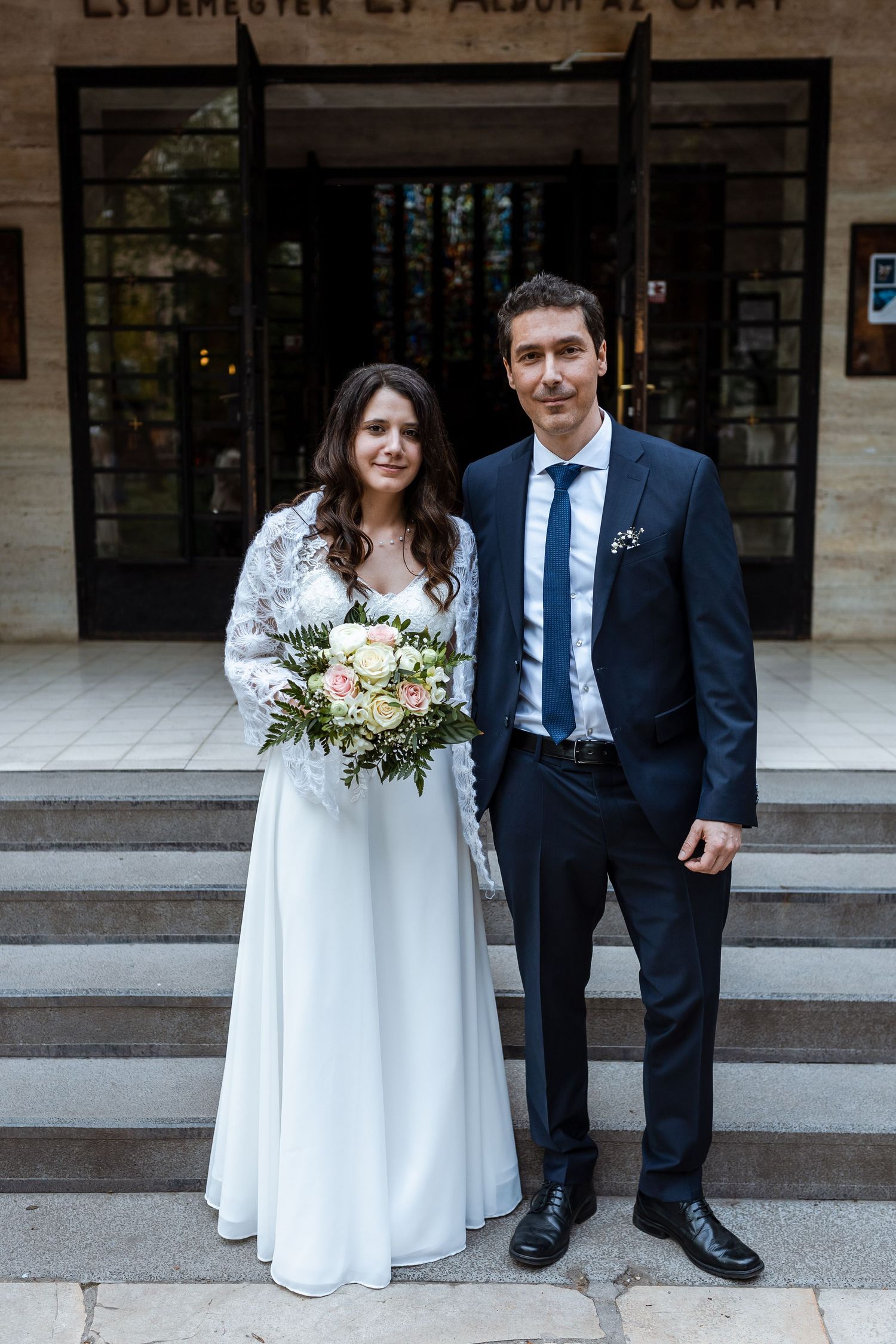 A couple in wedding attire poses on stone steps outside a building, shown in a series of four similar photos.