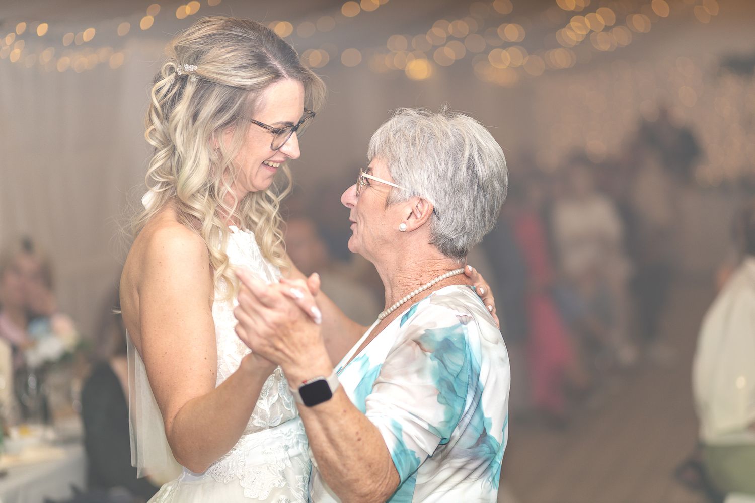 Couple dancing together in a romantic embrace during a celebration with blurred background lighting.