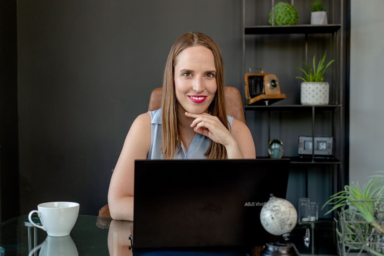 Business casual portrait with shelving and office decor visible in the background.