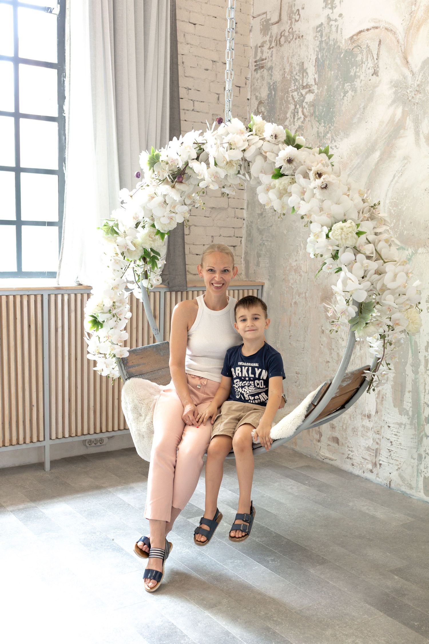 Studio photoshoot scene with white floral arch and modern interior design.