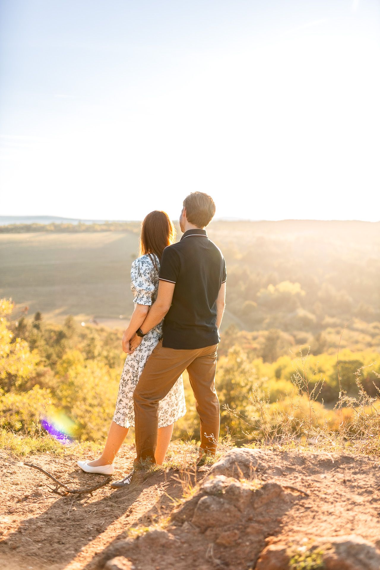 Couple sitting together on hilltop during sunset photography session.
