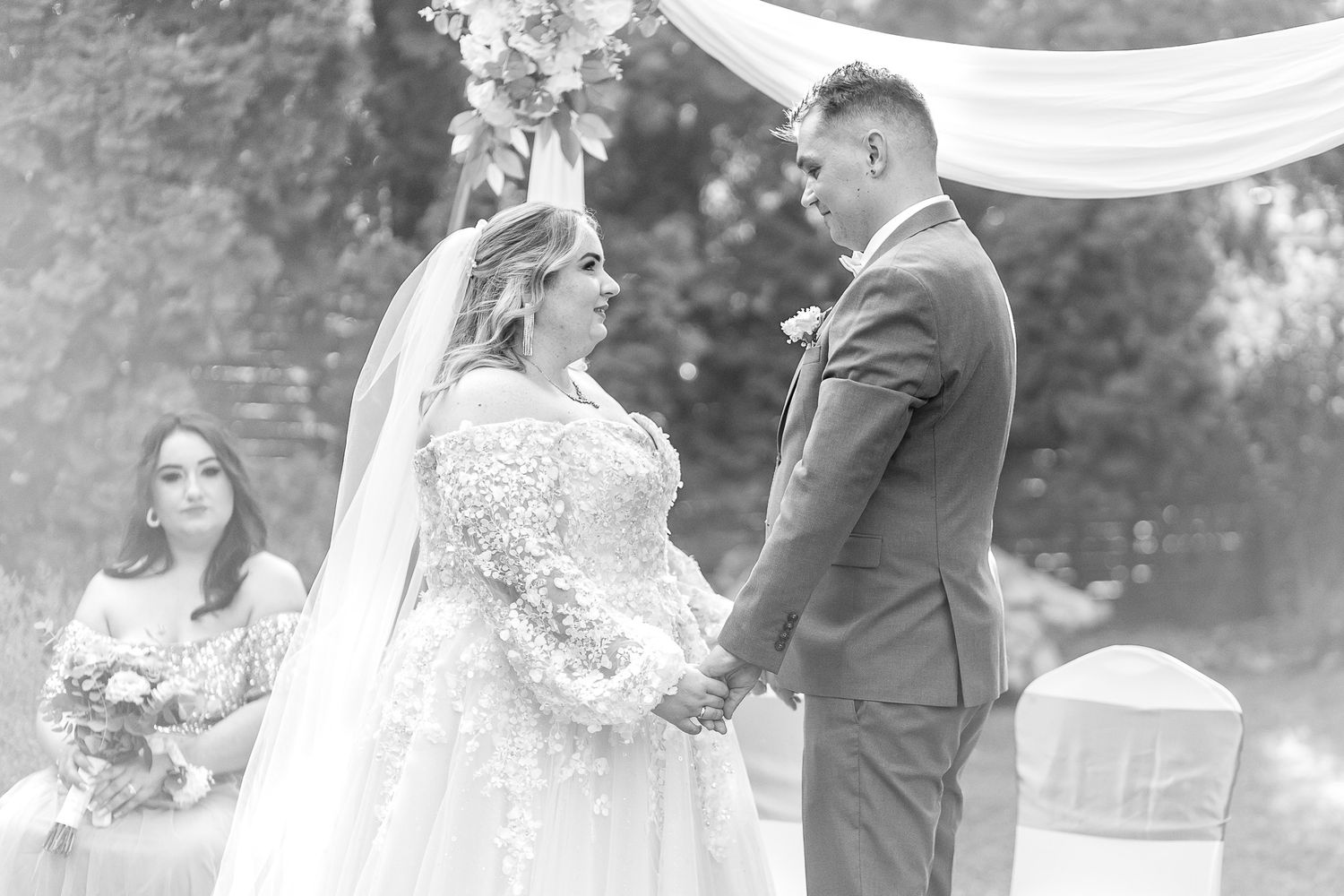 A black and white photo collage showing intimate moments from a romantic outdoor wedding ceremony and celebration.