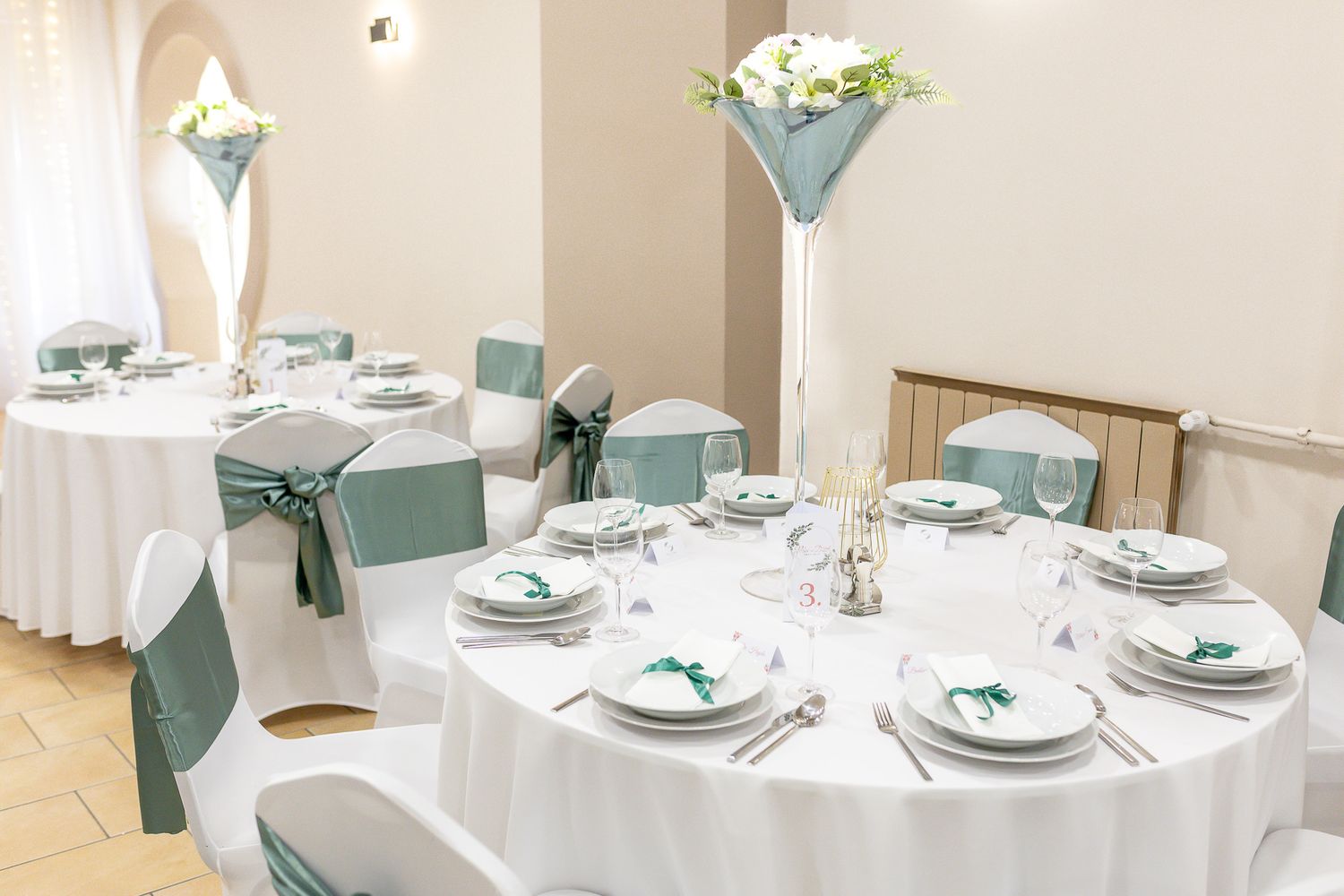 Elegant wedding reception tables decorated in soft mint green and white with floral centerpieces and place settings.