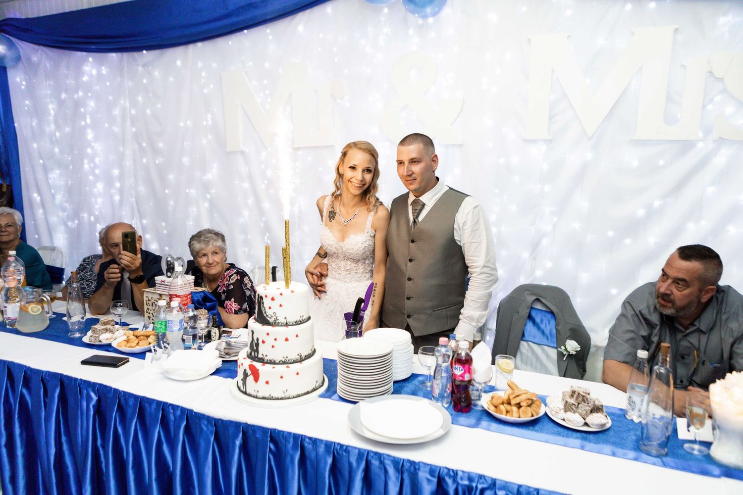 Wedding reception guests seated at tables decorated in royal blue and white linens enjoy a formal dining experience.