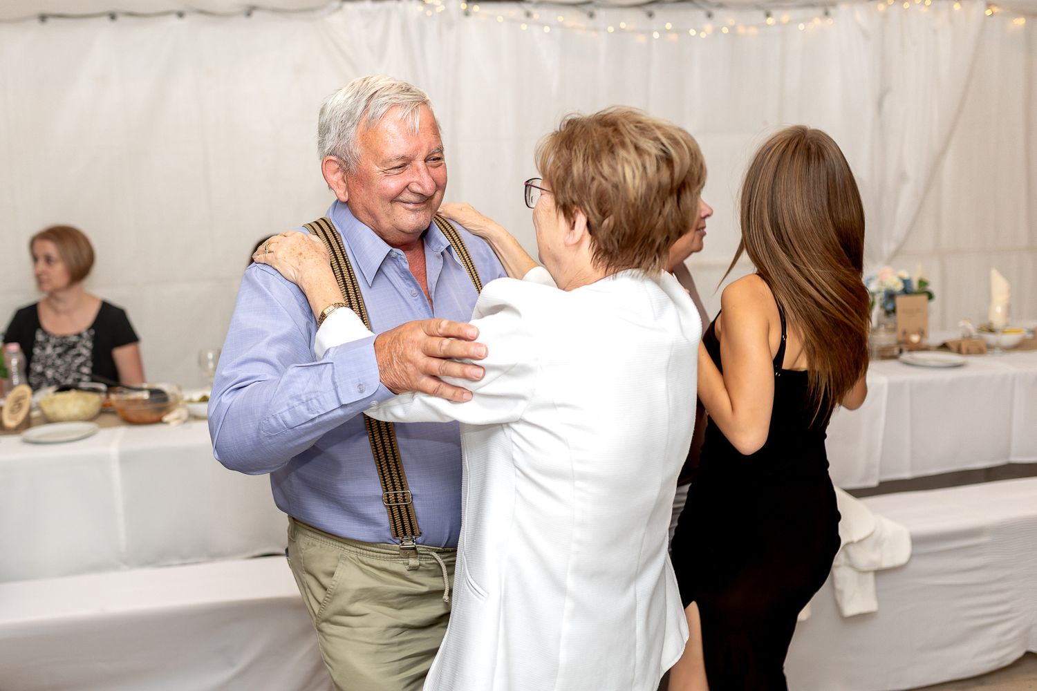 People dancing together at an elegant social event in a bright indoor venue.