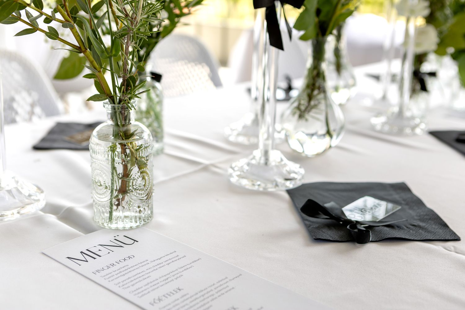 White tablescapes with delicate floral centerpieces in glass vases at an elegant event.