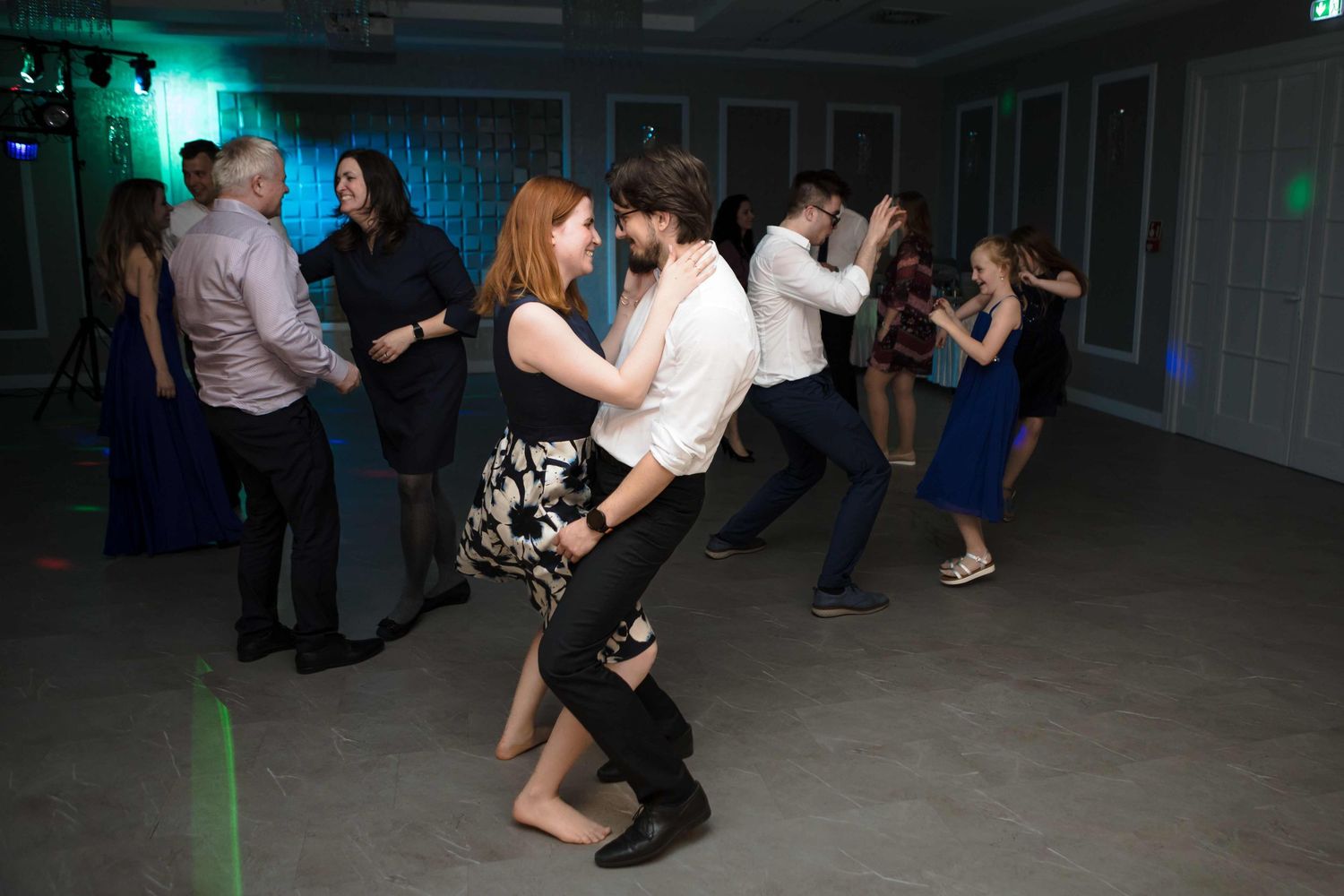People dancing together in a dimly lit room with green lighting effects.