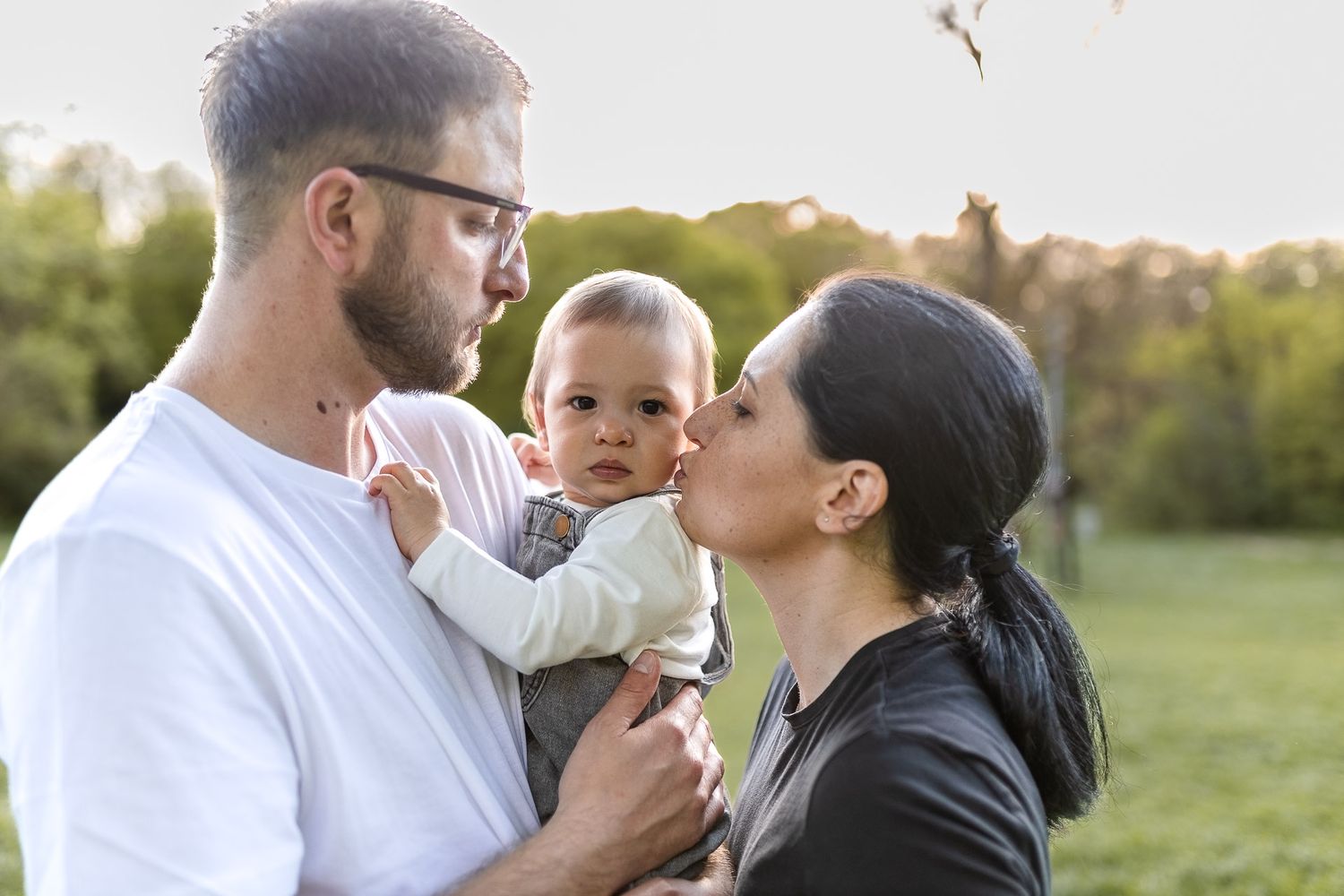 Intimate family portrait session outdoors with natural lighting and soft bokeh background.