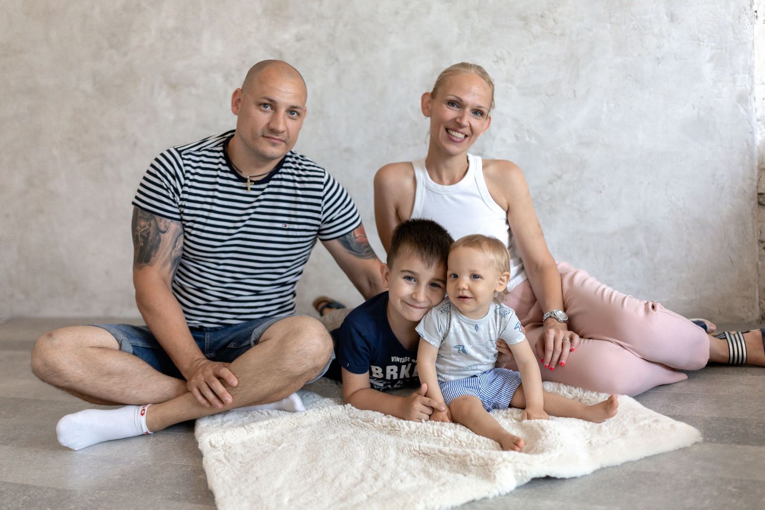 Casual family portrait session on floor with white textured backdrop.