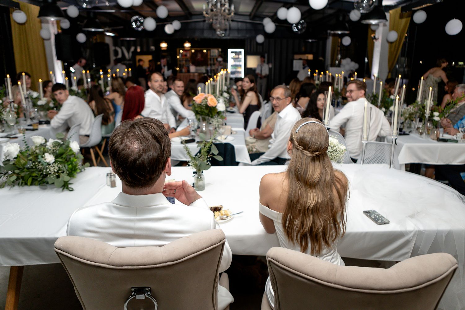 Wedding reception table setup with elegant white decor and seating arrangements.