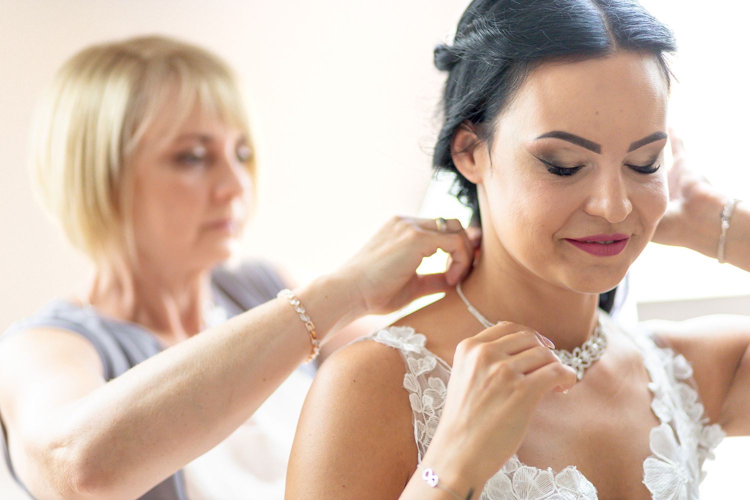 A group of bridesmaids in matching white robes sit together while getting ready for a wedding celebration.