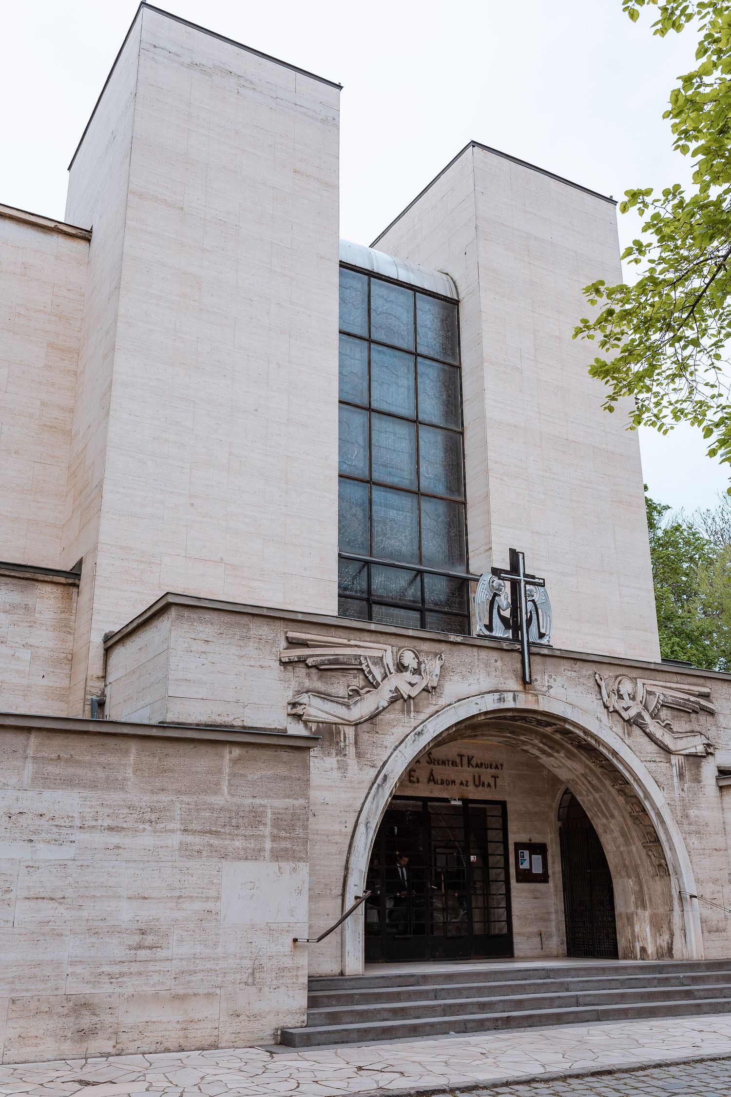 Modern church entrance with white stone walls, arched doorway, and tall vertical windows in contemporary architectural style.
