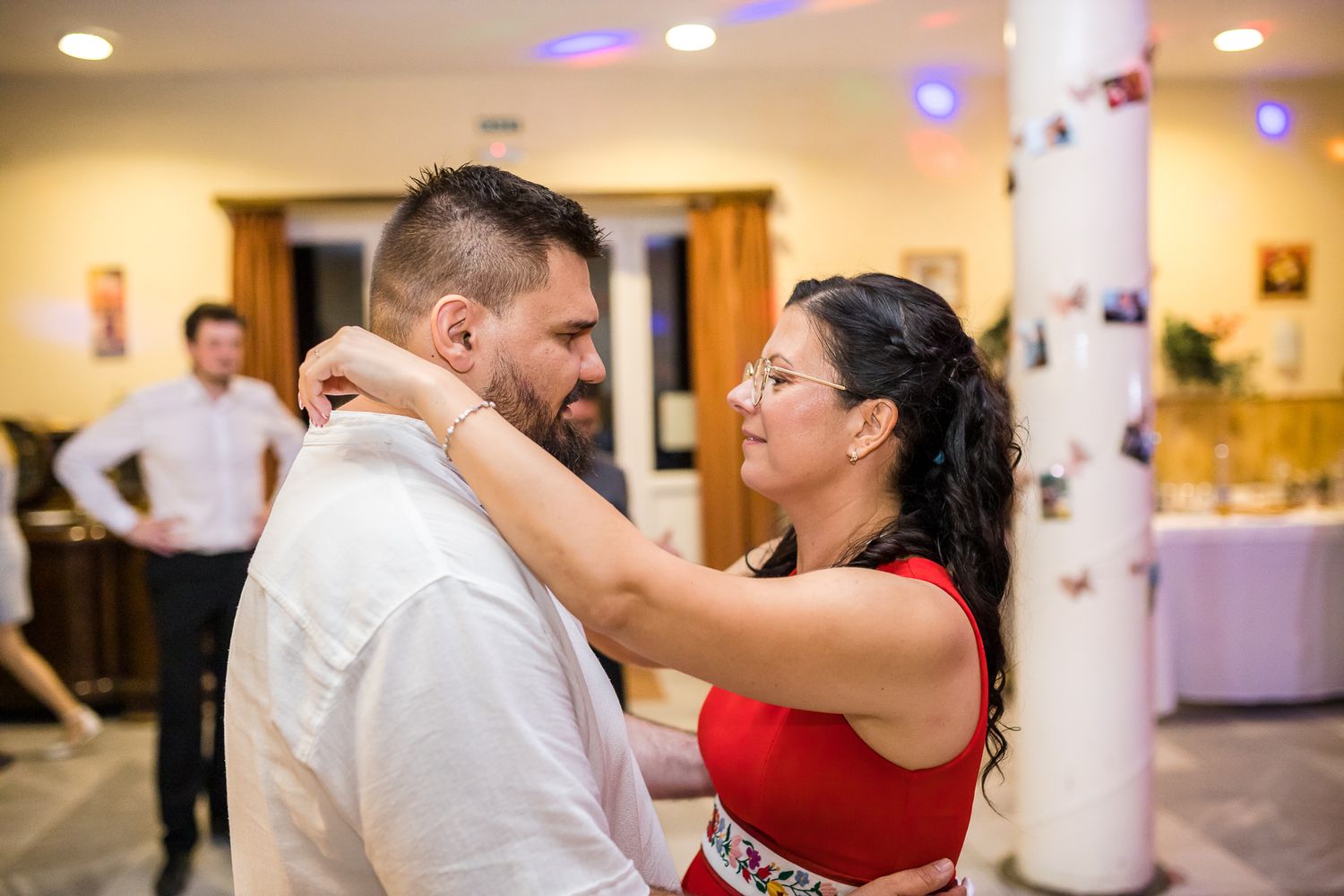 Couples dance together in an elegant ballroom setting with warm lighting and white decor.