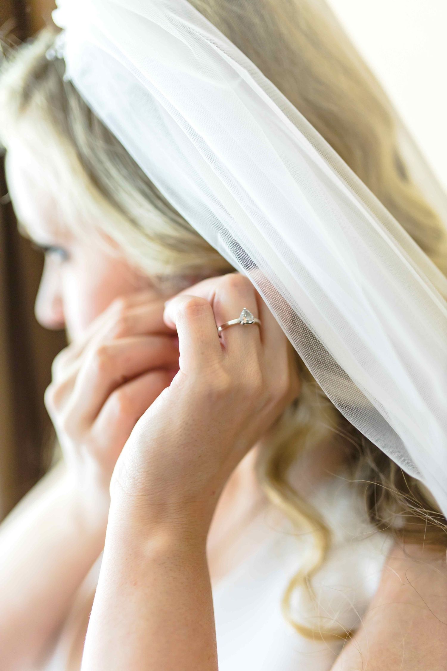 Close-up view of someone adjusting a delicate white wedding veil with gentle hands.