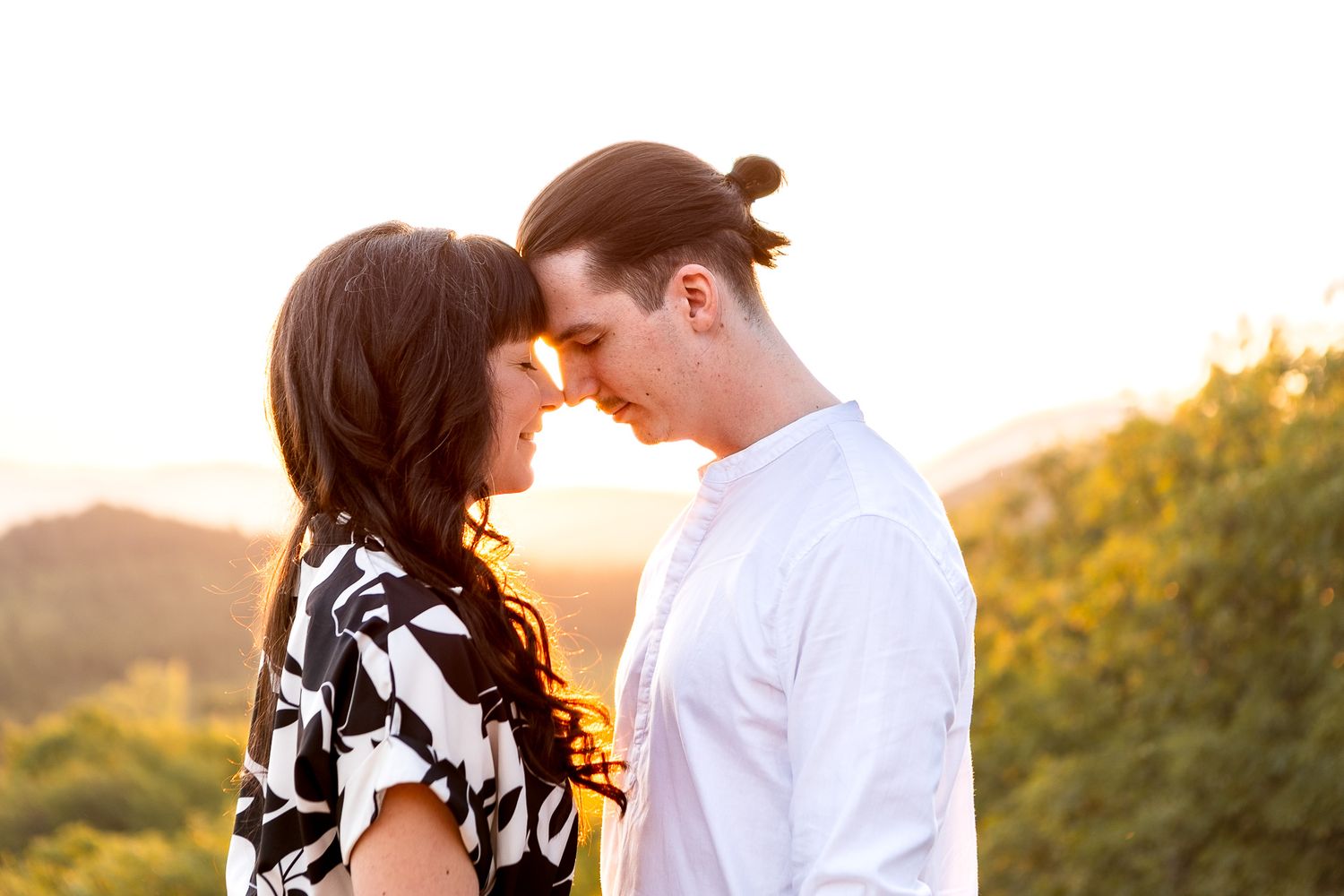A couple shares an intimate moment at sunset in a mountainous landscape.