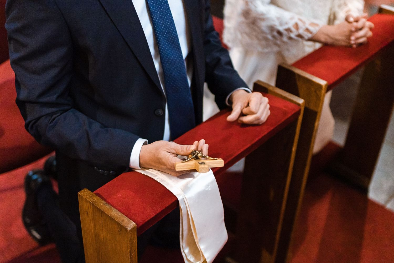 Person in formal attire holding a red box while presenting at a ceremony.