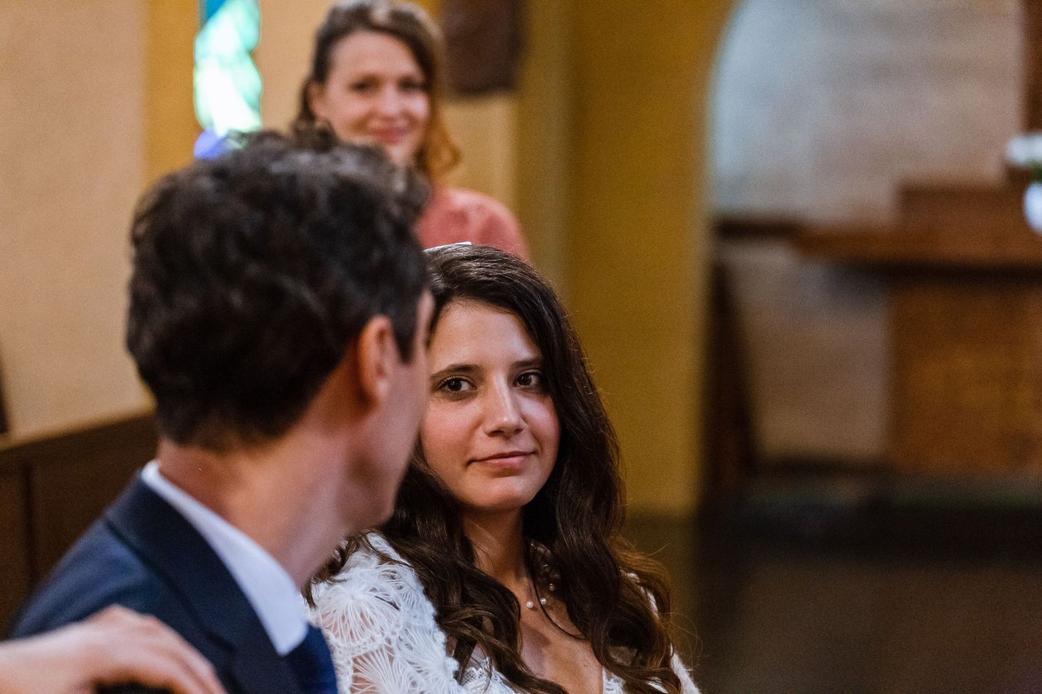 Wedding guests share joyful reactions and laughter during a celebration in a warm-lit indoor venue.