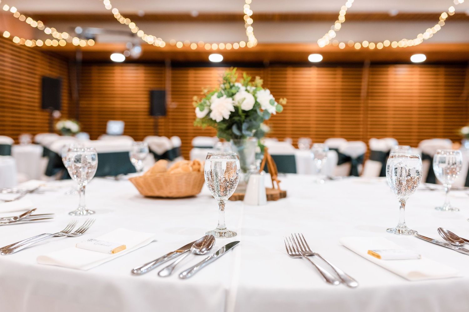 Elegant table settings with white linens, silverware, and wine glasses arranged for a formal dining event.