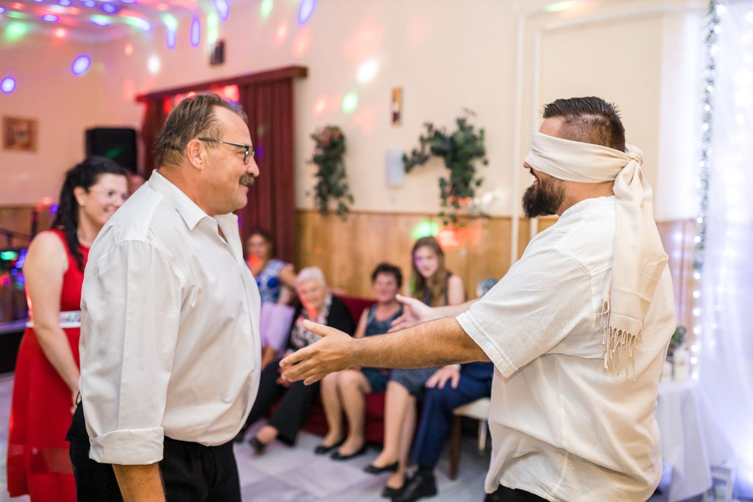 A couple dancing together at a wedding reception with colorful lights and decorations in the background.