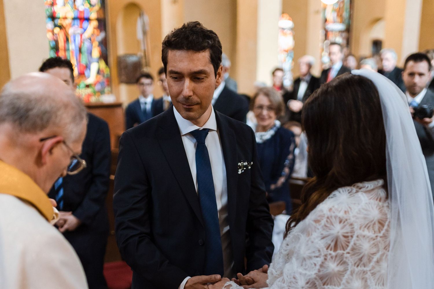 Wedding ceremony in a church with guests seated in pews and a couple at the altar in formal attire.