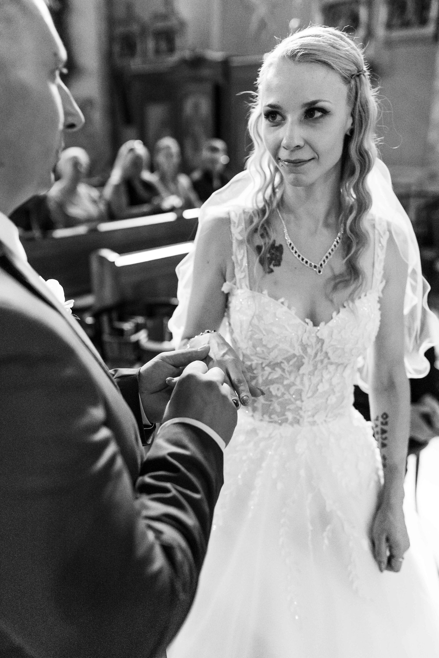 A bride in a white lace wedding dress smiles while dancing at her wedding reception.
