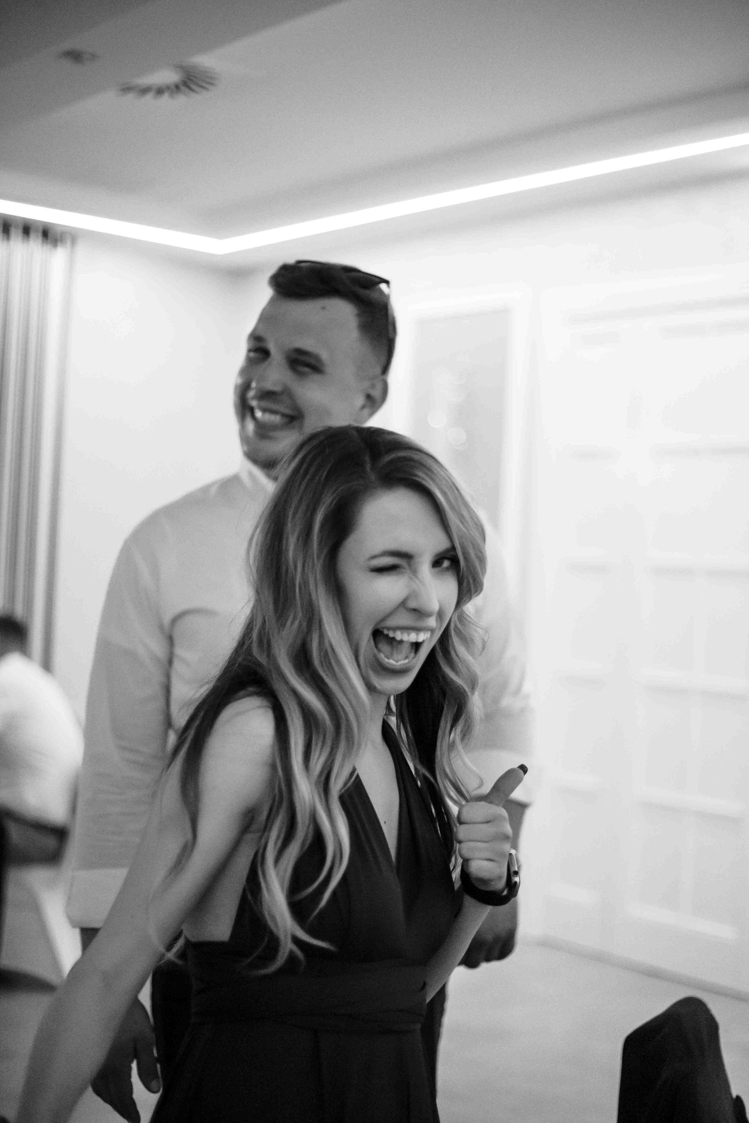 A candid black and white photo of a couple laughing together joyfully in a bright indoor setting.