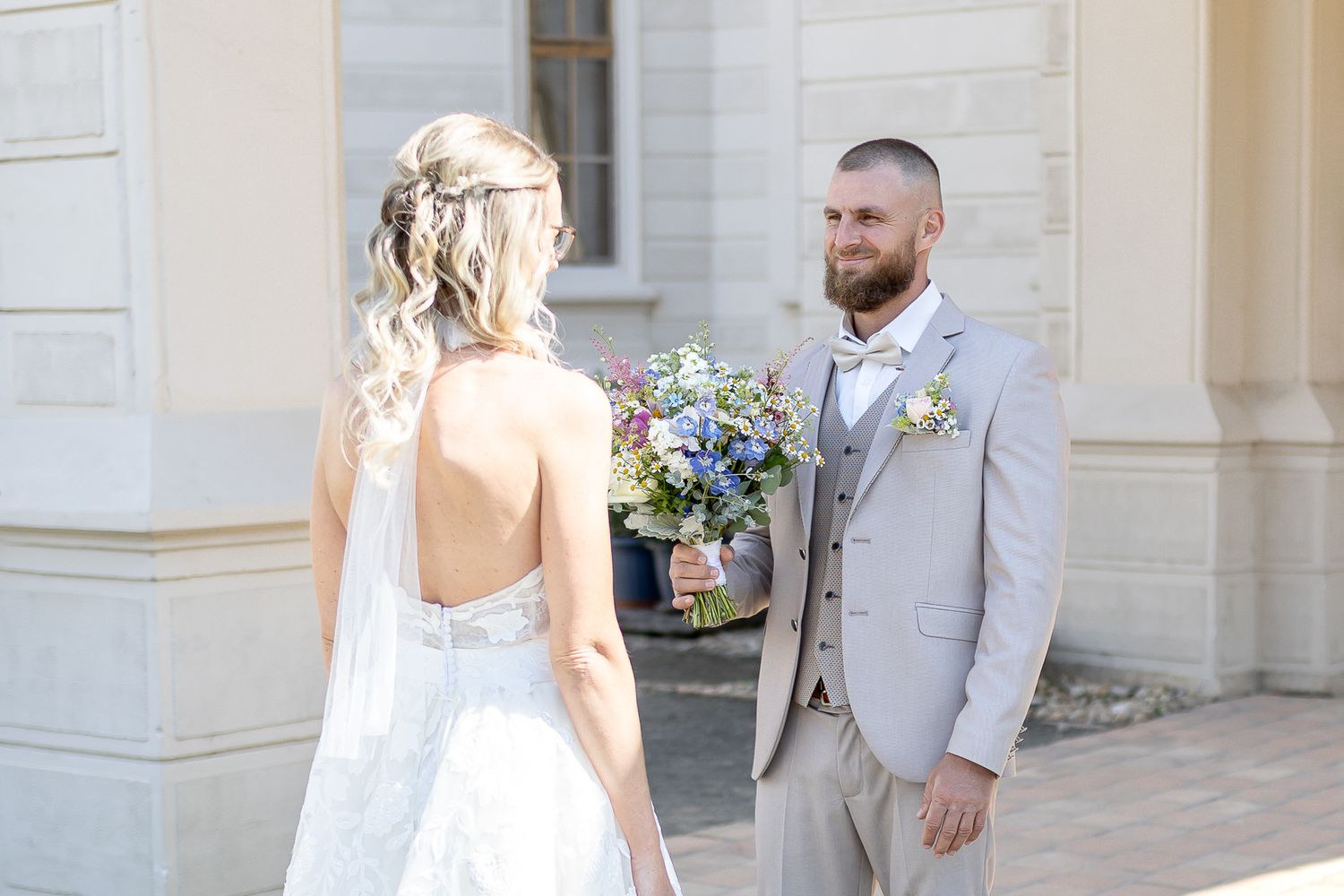 Bride and groom share a romantic moment outside an elegant stone building during their wedding celebration.