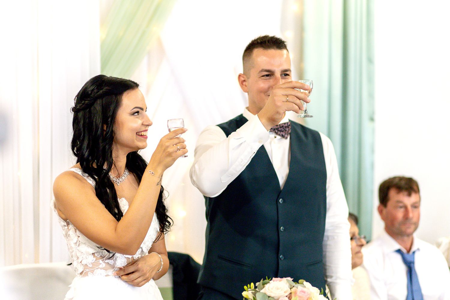 Wedding guests raise their glasses in a toast during an elegant reception celebration.