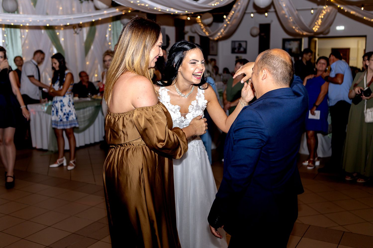 Couples dancing together on a wooden floor at an indoor wedding reception celebration.