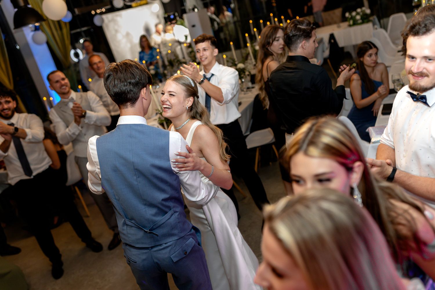Wedding reception guests dance energetically on a crowded dance floor.