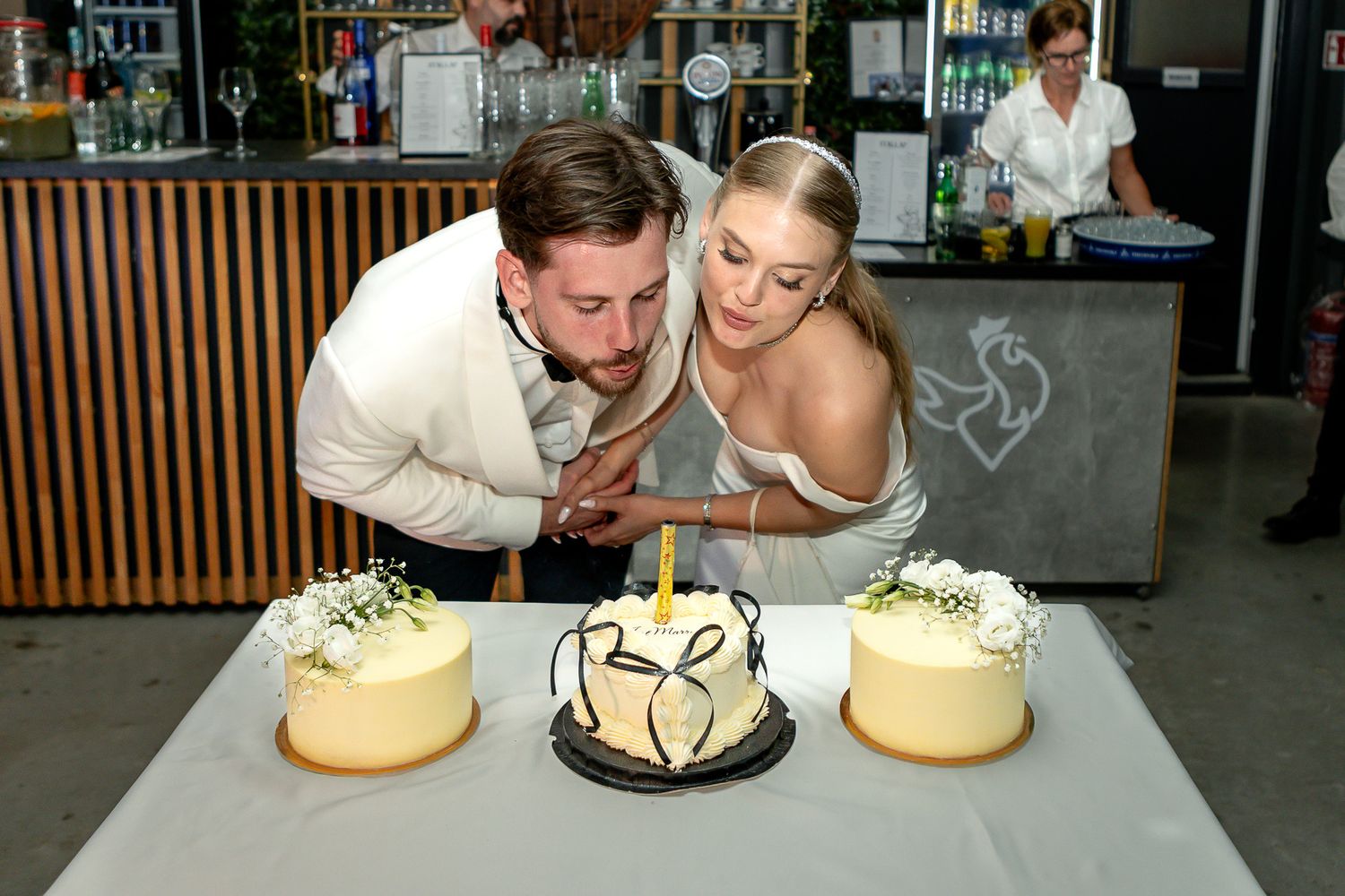 Wedding reception setup showing three decorated cakes and floral arrangements on display.