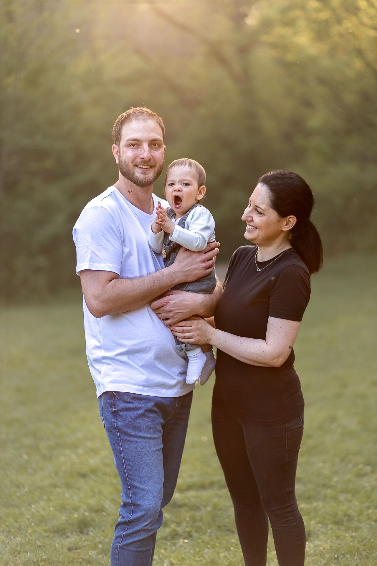 Family enjoying a playful moment together on a sunny day in a grassy field.